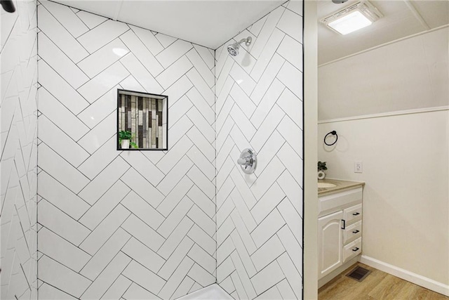 bathroom featuring vanity, wood-type flooring, and tiled shower