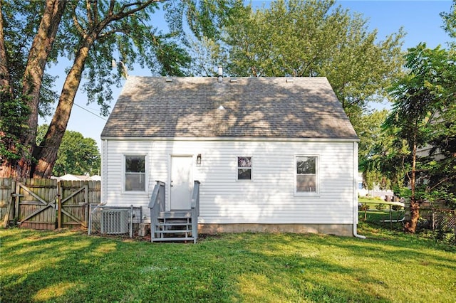 rear view of house featuring a lawn and central air condition unit