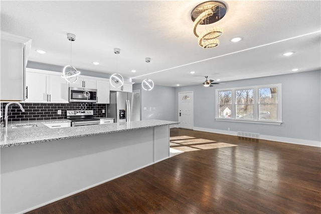 kitchen featuring white cabinets, appliances with stainless steel finishes, dark wood-type flooring, and sink