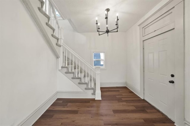 entryway featuring dark wood-type flooring and an inviting chandelier