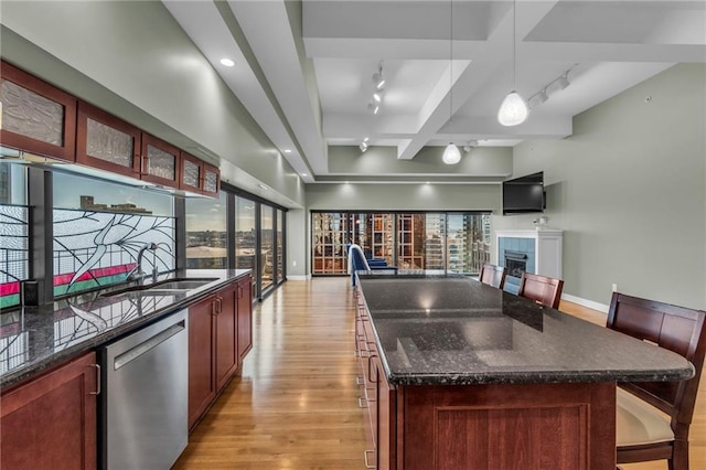 kitchen featuring track lighting, stainless steel dishwasher, decorative light fixtures, and a kitchen island