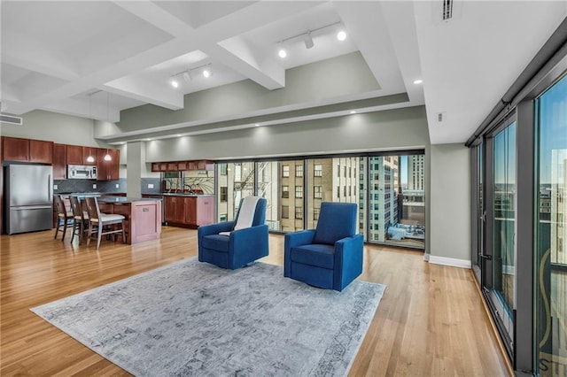 living room with a healthy amount of sunlight, light hardwood / wood-style floors, rail lighting, and coffered ceiling