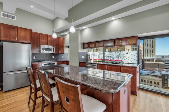 kitchen featuring pendant lighting, sink, light hardwood / wood-style flooring, appliances with stainless steel finishes, and a kitchen island