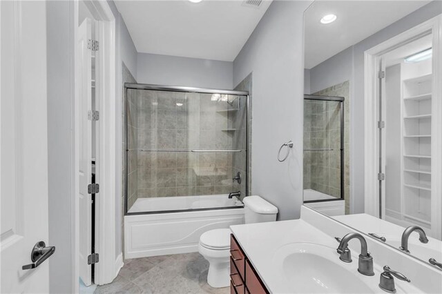 full bathroom with tile patterned floors, toilet, vanity, and combined bath / shower with glass door