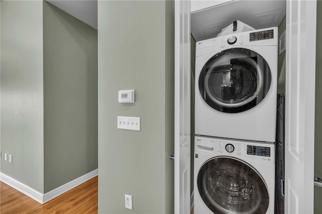 laundry room featuring stacked washer / dryer and hardwood / wood-style floors