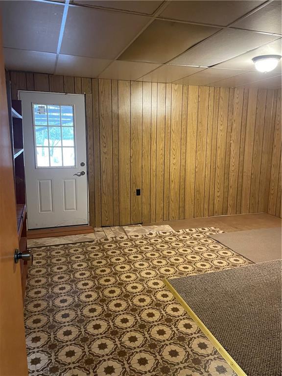 doorway with a paneled ceiling and wooden walls