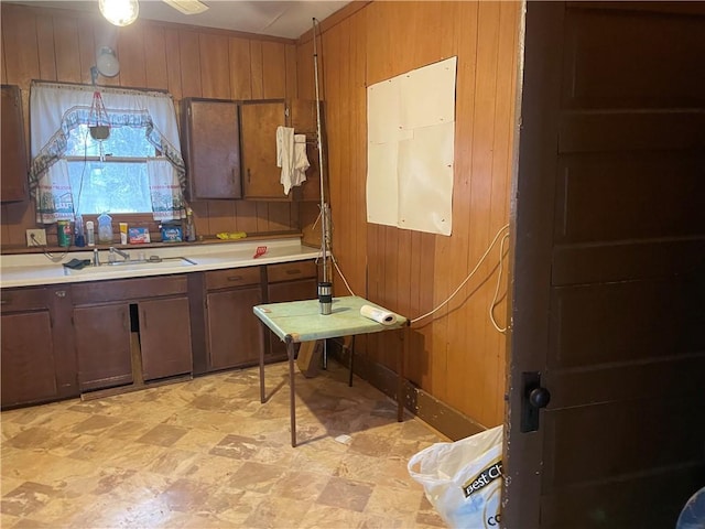 kitchen with light countertops, a sink, and wooden walls