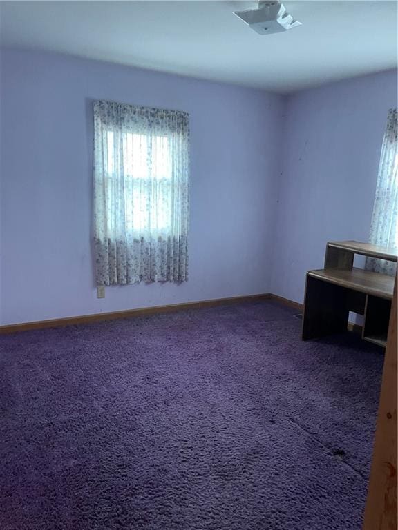 empty room featuring baseboards and dark colored carpet