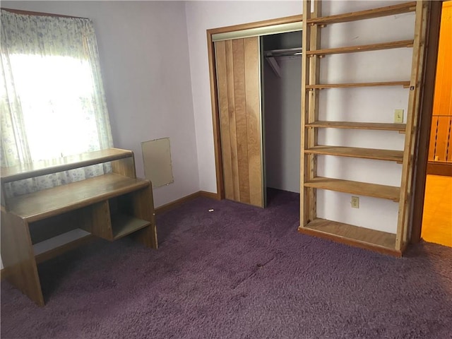 unfurnished bedroom featuring dark colored carpet, a closet, and baseboards