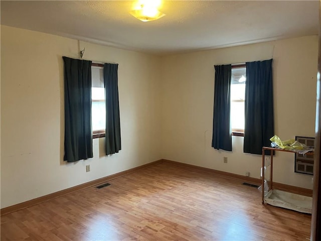 unfurnished room featuring baseboards, visible vents, and wood finished floors