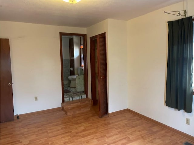 spare room featuring light wood-style floors, visible vents, and baseboards