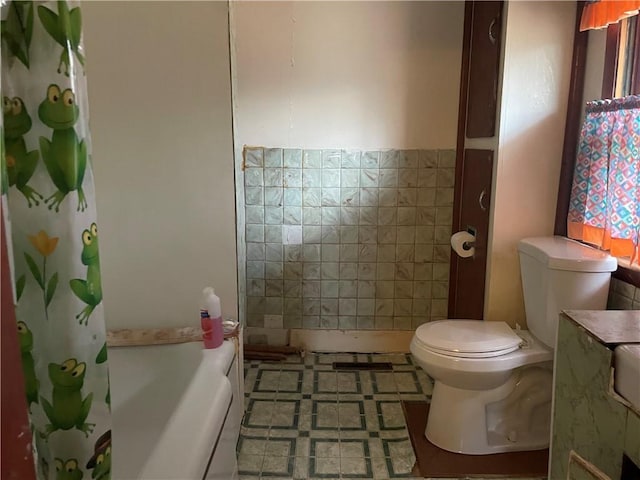 bathroom with toilet, shower / bath combination with curtain, and tile walls