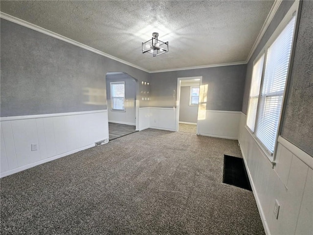 carpeted spare room featuring ornamental molding, a textured ceiling, and a chandelier