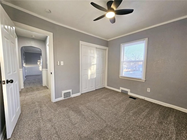 unfurnished bedroom featuring a closet, ceiling fan, crown molding, and carpet floors