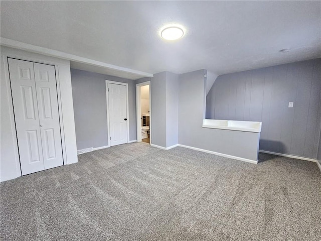 bonus room featuring carpet flooring and wood walls