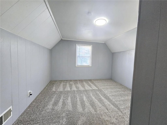 bonus room featuring carpet flooring, wood walls, and vaulted ceiling