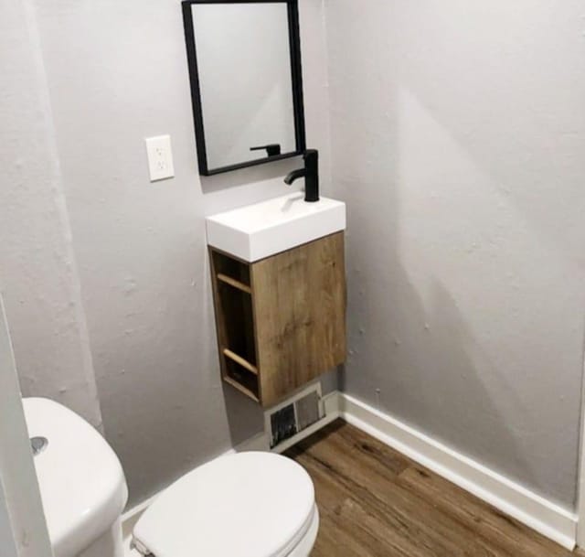 bathroom with toilet, vanity, and hardwood / wood-style flooring