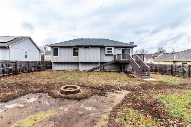 back of property with a fire pit and a deck