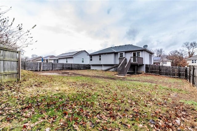 rear view of property featuring a deck and a lawn