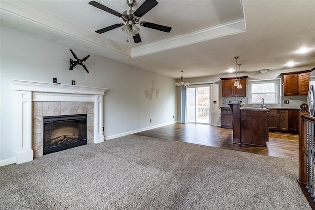 kitchen with a tile fireplace, a center island, a raised ceiling, pendant lighting, and dark carpet