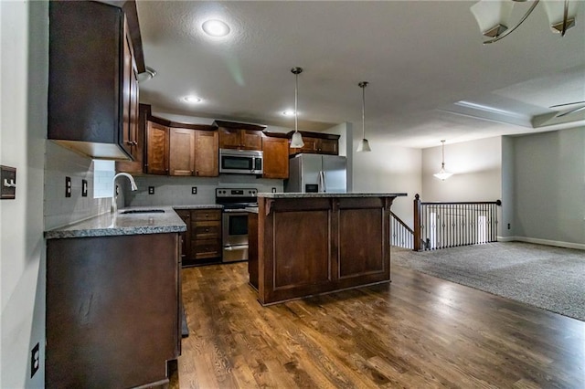 kitchen featuring appliances with stainless steel finishes, dark hardwood / wood-style flooring, sink, pendant lighting, and a center island