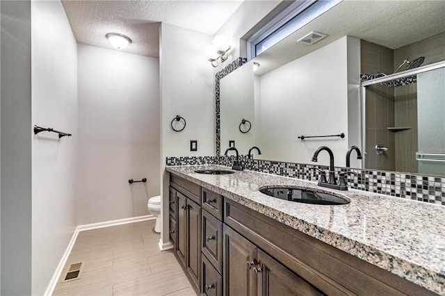 bathroom with vanity, a shower with door, backsplash, toilet, and a textured ceiling