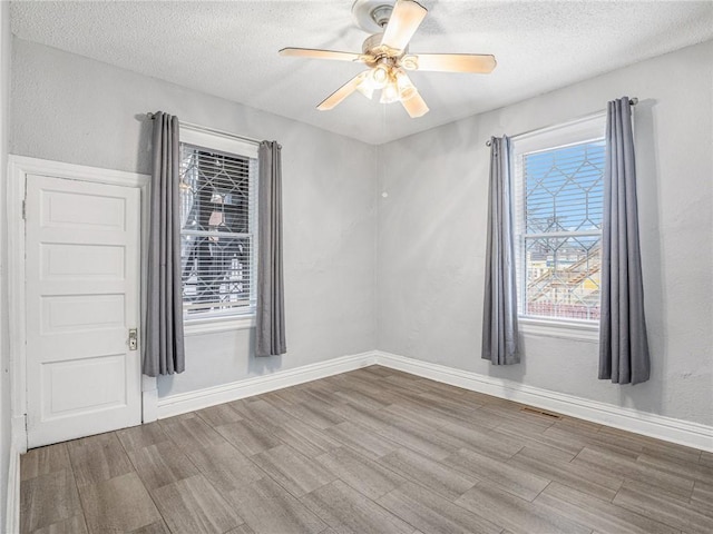 spare room featuring hardwood / wood-style floors, ceiling fan, and a textured ceiling