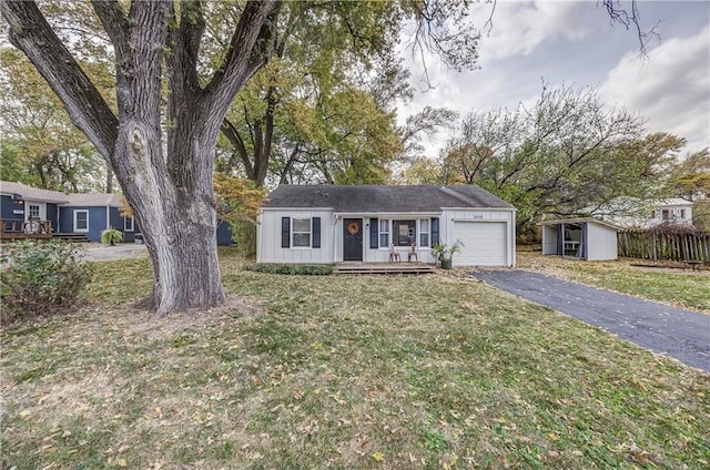 ranch-style house with a front yard, a porch, a garage, and a storage shed