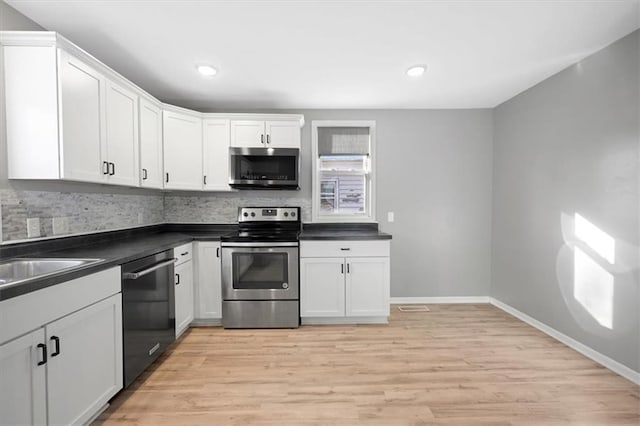 kitchen with white cabinets, backsplash, stainless steel appliances, and light hardwood / wood-style flooring