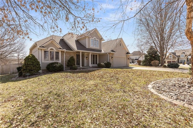 view of front of home with fence, concrete driveway, a front yard, a garage, and stone siding