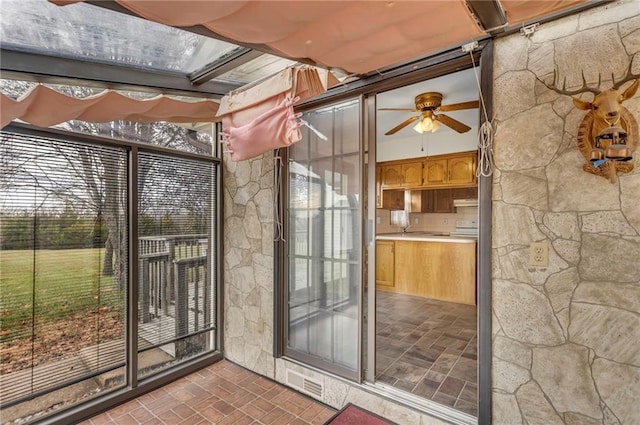 unfurnished sunroom featuring ceiling fan