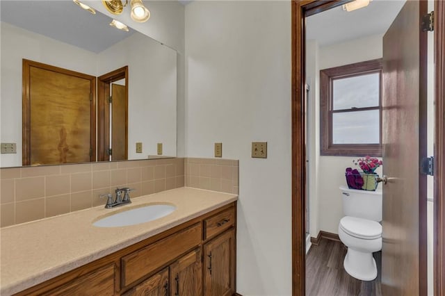 bathroom featuring hardwood / wood-style flooring, vanity, toilet, and tasteful backsplash