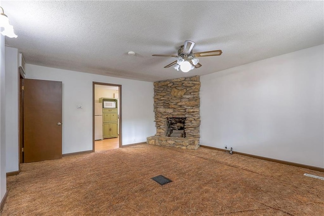 unfurnished living room featuring a textured ceiling, carpet floors, and a stone fireplace