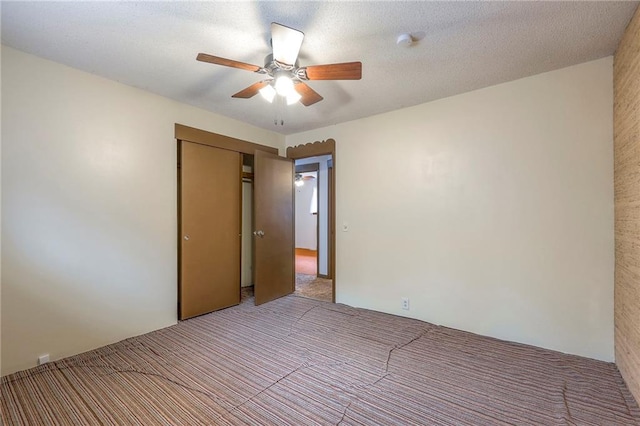 unfurnished room with ceiling fan and a textured ceiling