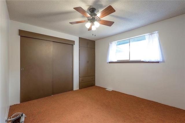 unfurnished bedroom with a textured ceiling, carpet floors, and ceiling fan