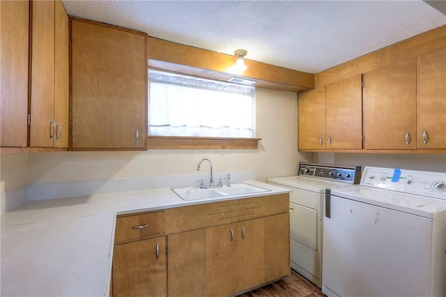 laundry room featuring a textured ceiling, cabinets, sink, and washing machine and clothes dryer