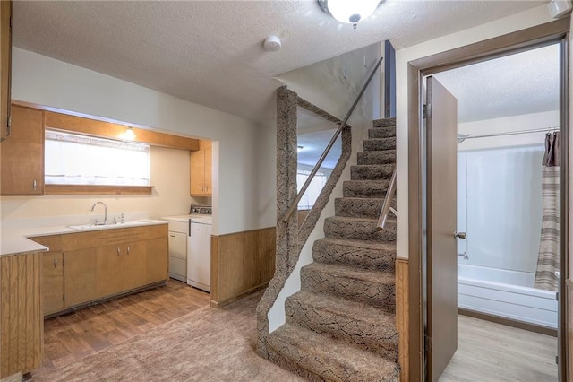 stairway featuring a textured ceiling, wood-type flooring, independent washer and dryer, and sink