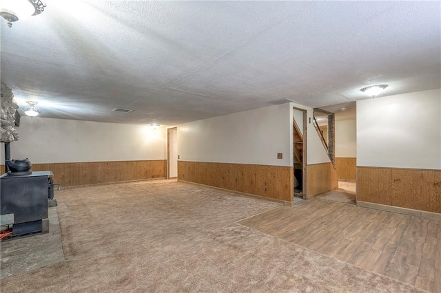 basement featuring wood walls, carpet floors, and a textured ceiling