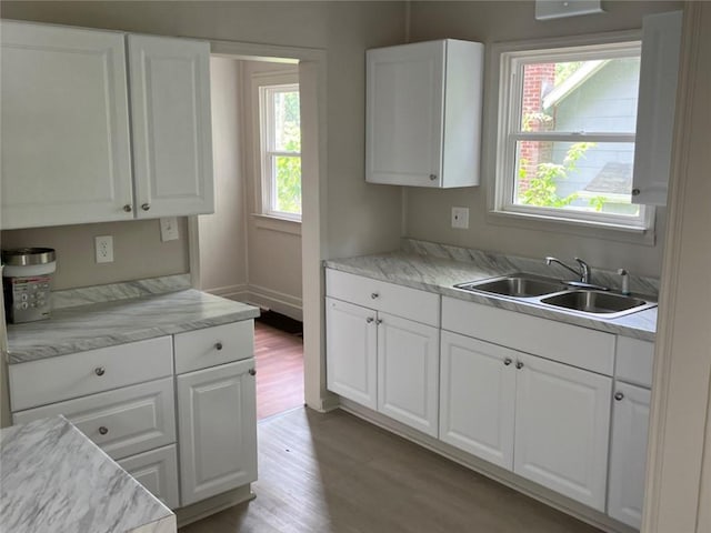 kitchen with white cabinets, light hardwood / wood-style floors, and sink