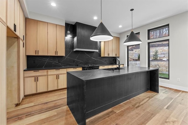 kitchen with a kitchen island with sink, sink, pendant lighting, and light brown cabinets