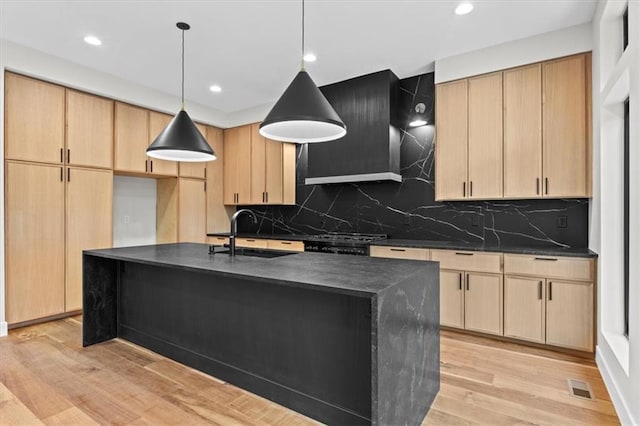 kitchen featuring light brown cabinets, light hardwood / wood-style floors, sink, and a kitchen island with sink