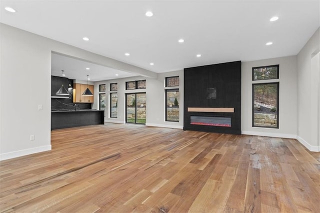 unfurnished living room featuring a large fireplace and light hardwood / wood-style floors