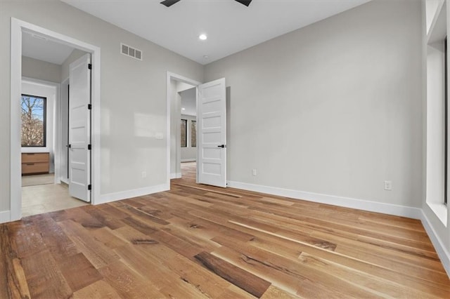 unfurnished bedroom with ceiling fan, ensuite bathroom, and wood-type flooring