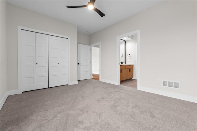 unfurnished bedroom featuring connected bathroom, ceiling fan, a closet, and light carpet