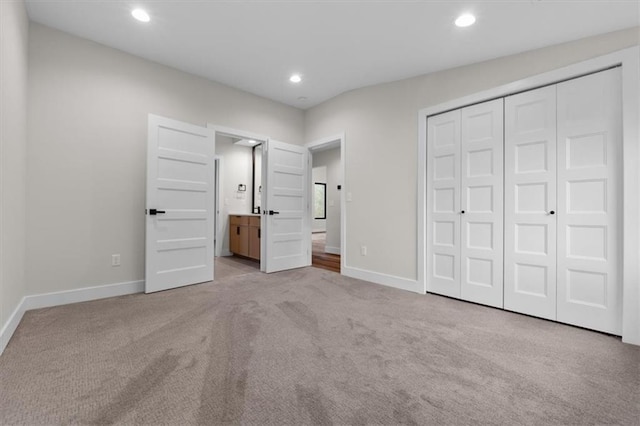 unfurnished bedroom featuring light colored carpet, ensuite bath, and a closet