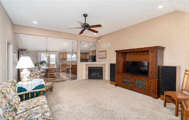 living room featuring a tile fireplace, ceiling fan, sink, light colored carpet, and vaulted ceiling