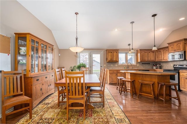 dining area with sink, dark wood-type flooring, and vaulted ceiling