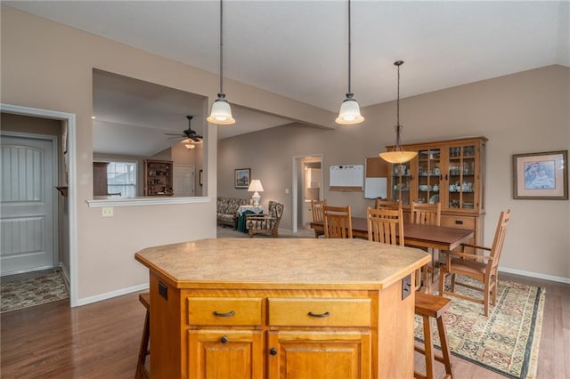 kitchen with pendant lighting, lofted ceiling, dark hardwood / wood-style floors, ceiling fan, and a kitchen island