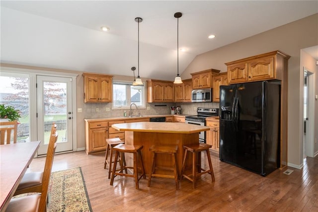 kitchen featuring tasteful backsplash, wood-type flooring, lofted ceiling, a kitchen island, and black appliances