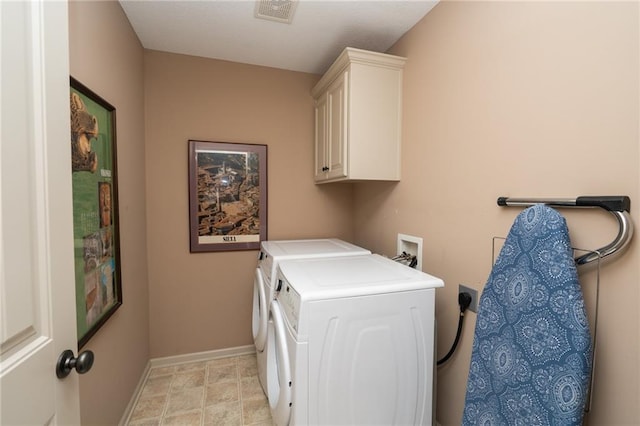 clothes washing area featuring cabinets and separate washer and dryer